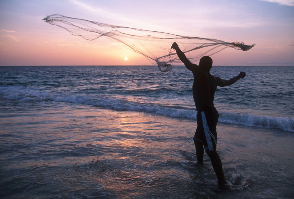 A fisherman casts his fishing net on the coast at sunset Gabon