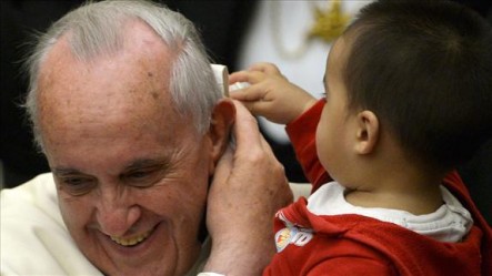 El Papa juega junto a un pequeño niño, que toma el solideo en sus manos.