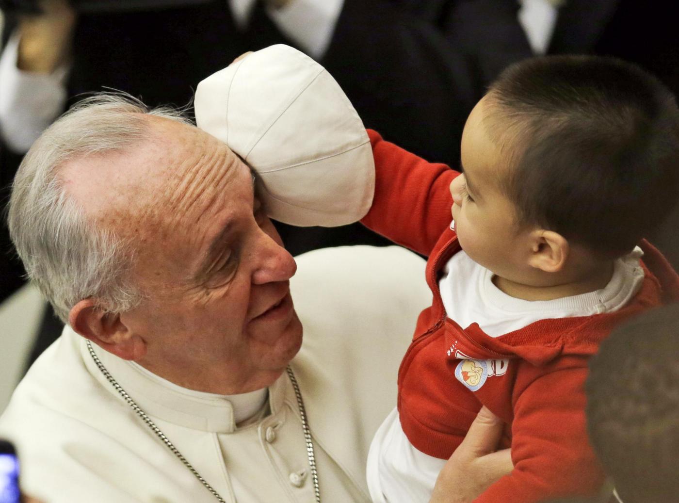 A child takes off Pope Francis' white zucchetto, or skullcap, during a meeting with children and volunteers of the Santa Marta Vatican Institute, at the Vatican, Saturday, Dec. 14, 2013. (AP Photo/Gregorio Borgia)